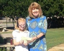 A young girl gives a donation check to a woman from The WARM Place.