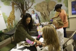 A woman leads children in a crafting activity.