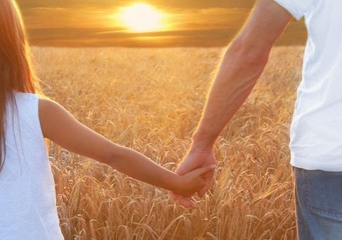 Father with his daughter at sunset in barley field