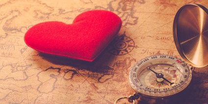 Valentine day background. Old compass on vintage map with red heart. Retro filter. Direction to real love of your heart concept.