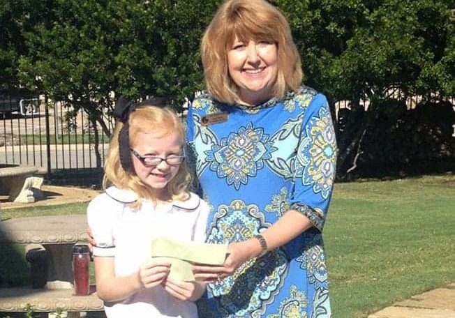 A young girl gives a donation check to a woman from The WARM Place.