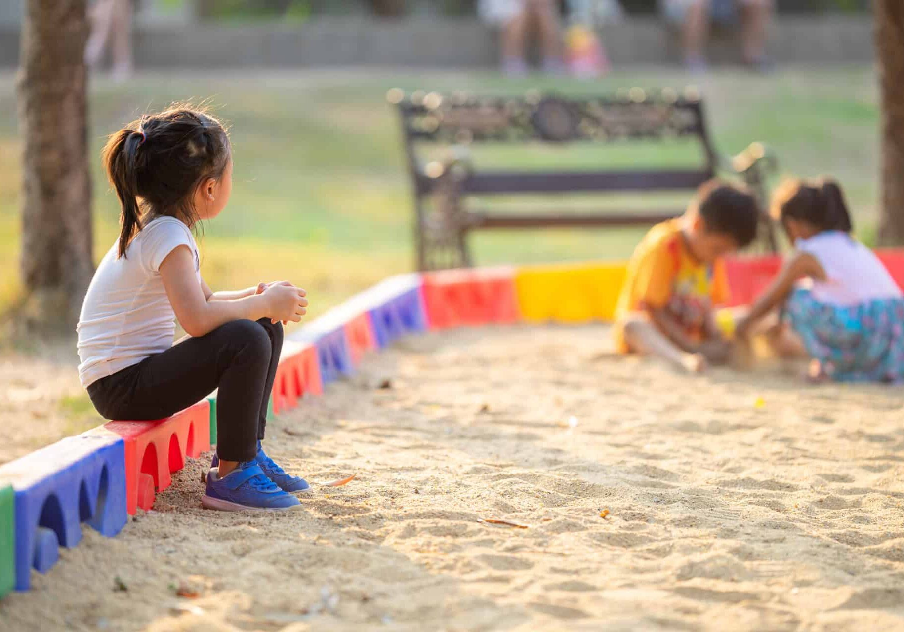 Little,Girl,Sitting,Lonely,Watching,Friends,Play,At,The,Playground.the
