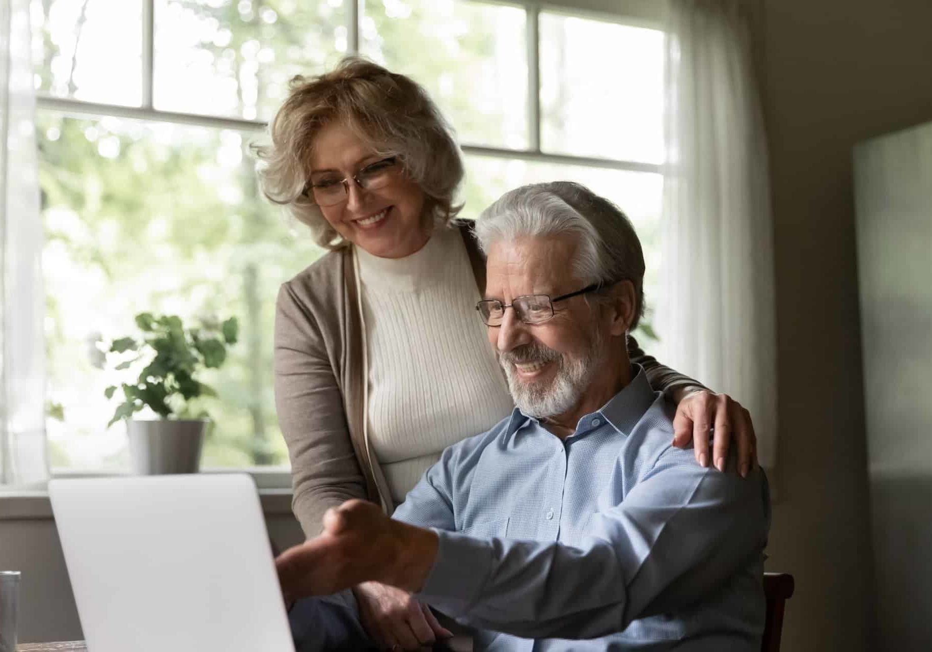 Happy,Mature,Caucasian,Couple,Look,At,Laptop,Screen,Pay,Bills