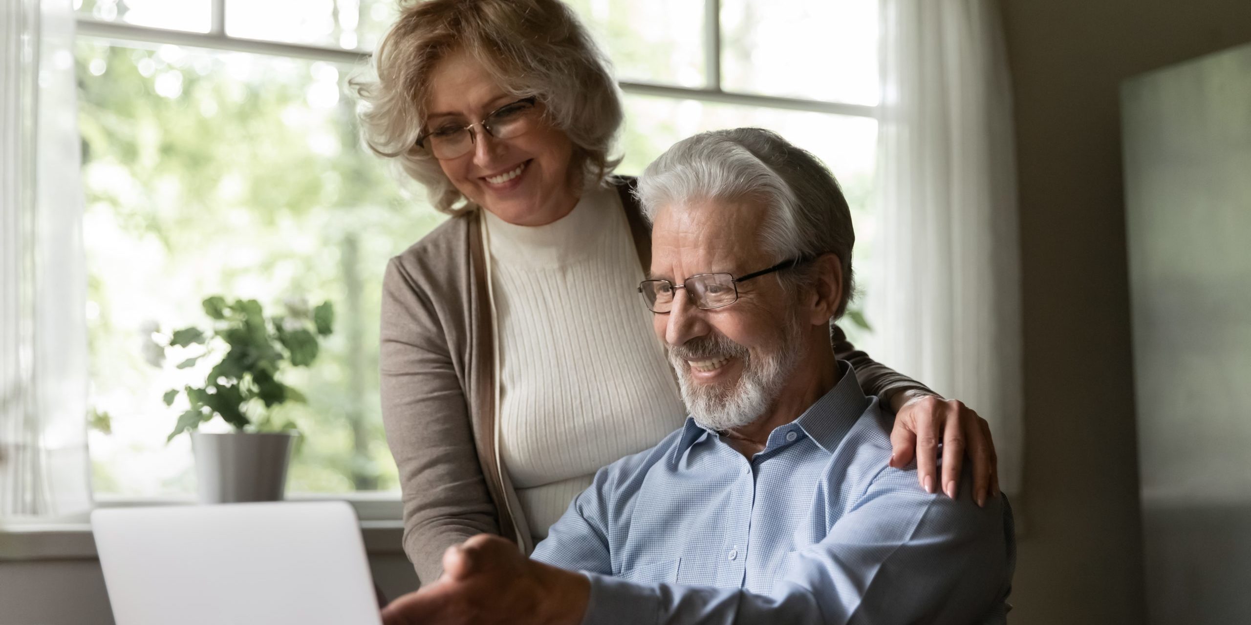 Happy,Mature,Caucasian,Couple,Look,At,Laptop,Screen,Pay,Bills